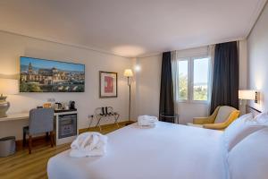 a hotel room with a large white bed and a desk at Hesperia Córdoba in Córdoba