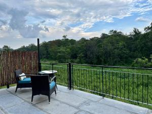 a patio with two chairs and a table and a fence at Machaan Wilderness Lodge Nagarahole in Srimangala
