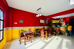 un restaurante con paredes rojas y amarillas y mesas y sillas de madera. en MC's L Transient House en Bantay