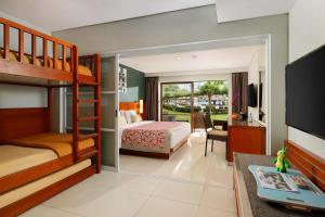 a bedroom with a bunk bed and a living room at Bali Dynasty Resort in Kuta