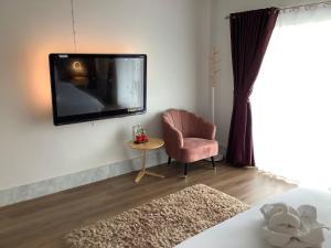 1 dormitorio con TV en la pared y silla en ฝันดี Fandicottage en Betong