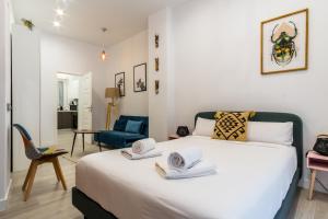 a bedroom with a large white bed with a blue chair at 2 habitaciones 2 baños- Moderno y Acogedor - Imperial in Madrid