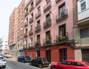 ein rosafarbenes Gebäude mit Autos auf einer Straße in der Unterkunft 2 habitaciones 2 baños- Moderno y Acogedor - Imperial in Madrid