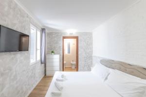 - une chambre blanche avec un lit et une télévision murale dans l'établissement Home Holiday Rome - 2° Floor, à Rome