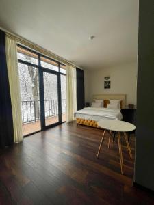um quarto com uma cama, uma mesa e uma grande janela em Wald Hotel Lagodekhi Rooms em Lagodekhi
