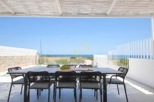 a dining table and chairs on a patio with the ocean at TD Villa Grecale Modern Luxury Villa with SeaView in Capitolo