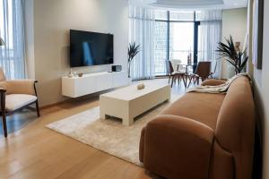 uma sala de estar com um sofá e uma televisão em AYA Boutique - Cozy 1BR Apartment with Panoramic City Views em Dubai
