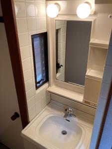 ein Bad mit einem Waschbecken und einem Spiegel in der Unterkunft Nostime lodge 女性限定 female only in Kitakyūshū