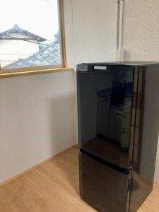 una nevera negra en una habitación con ventana en Nostime lodge 女性限定 female only en Kitakyushu