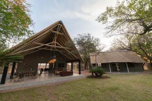 a house with a thatched roof and a yard at Tomo Safari Lodge in Hoedspruit