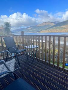 patio con mesa y silla en el balcón en Cottage on the Loch, en Arrochar