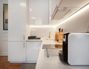 eine Küche mit weißen Schränken und einer Mikrowelle in der Unterkunft Art Borelli Vranski Apartment by Irundo in Zagreb