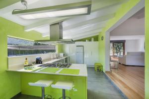 アルクーディアにあるVilla Puig Xaconsの緑の壁、白いカウンターとスツール付きのキッチン