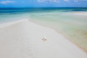 Dikoni的住宿－Ycona Eco-Luxury Resort, Zanzibar，坐在海洋白色沙滩上的船