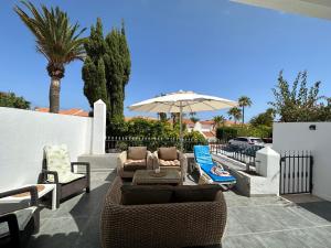 un patio con divano, sedie e ombrellone di Sunningdale Village Golf Del Sur a San Miguel de Abona