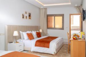 a bedroom with two beds and a desk and a window at Hotel Golden Sunset Dakhla in Dakhla