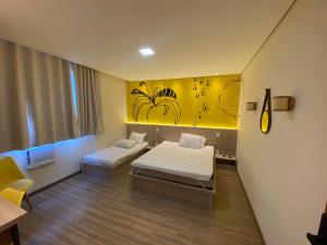 a room with two beds and a yellow wall at Pousada Boutique Raio de Luz in Ouro Preto