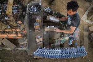 a man is working with a bunch of metals at Ban Na Pia - Family Home stay in Muang Phônsavan