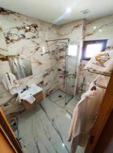 a marble bathroom with a shower and a sink at Hotel Golden Sunset Dakhla in Dakhla