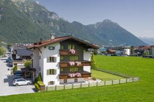 een huis in een veld met bergen op de achtergrond bij Alpenherz Ferienwohnungen in Pertisau