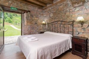 a bedroom with a bed and a stone wall at Leyendas del Miera in Liérganes