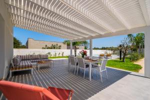 a patio with a white pergola and a table and chairs at Villa DellaTerra in Alcamo