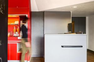 einen weißen Kühlschrank in einem Zimmer mit roter Wand in der Unterkunft hotelF1 Nancy Nord Bouxieres in Bouxières-aux-Dames