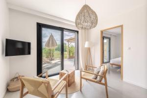 ein Wohnzimmer mit einem Sofa, Stühlen und einem TV in der Unterkunft VILLA KASBAR avec spa privé 4 étoiles in Tizac-de-Curton