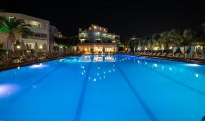 a large blue swimming pool at night at Atrion Resort Hotel in Agia Marina Nea Kydonias