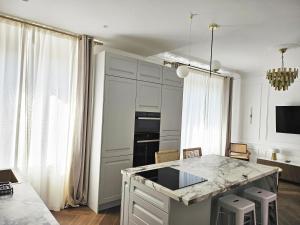 - une cuisine avec des placards blancs et un comptoir en marbre dans l'établissement Le petit Versailles - T2 au centre-ville, à Grenoble