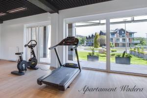 - une salle de sport avec deux appareils d'exercice et une grande fenêtre dans l'établissement Apartament Basior, Laguna Beskidów, à Zarzecze