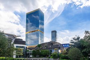 un rascacielos de cristal alto frente a un edificio en WAIFIDEN Guangzhou Grand View Golden Palace Apartment - Free shuttle bus during the Canton Fair en Guangzhou