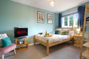 a bedroom with a bed with a television and a chair at Charming 4 Bedroom House in Prime Location - Close to City Centre - Free Parking, Smart TVs and Landscaped Garden by Yoko Property in Milton Keynes