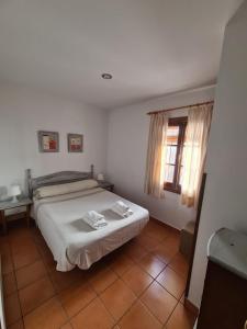 una camera con un letto bianco e una finestra di Casa Virués a Grazalema