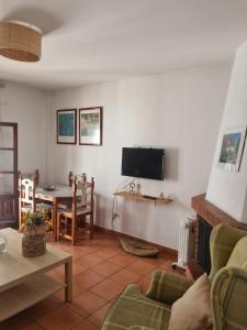 sala de estar con sofá y TV en la pared en Casa Virués, en Grazalema