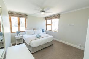 a white bedroom with a bed and two windows at Villas Marina On The Beach in Port Elizabeth