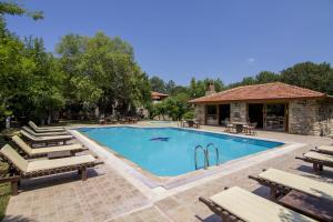 a large swimming pool with benches and a building at Doga Apartments in Kayakoy