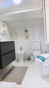 La salle de bains blanche est pourvue de toilettes et d'un lavabo. dans l'établissement Ático combarro, à Combarro