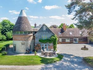 an old stone house with a turret and a yard at The Oast House - Hartley Wine Estate in Alton