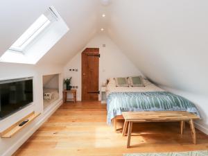 a attic bedroom with a bed and a tv at The Rookery in Burford