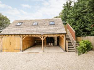 a large wooden garage with a staircase and a house at The Rookery in Burford