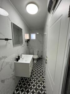 a white bathroom with a sink and a toilet at הטרקלין של לינוי - 5 דקות נסיעה מהים in Ashkelon