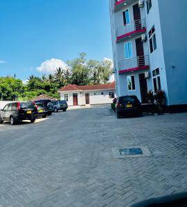 a parking lot with cars parked next to a building at Lomes cozy home in Dar es Salaam