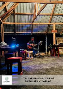 a man is playing a guitar in a room at Forestar Villa and Restaurant in Nittambuwa