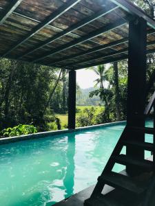 a swimming pool with a wooden pergola over it at Forestar Villa and Restaurant in Nittambuwa