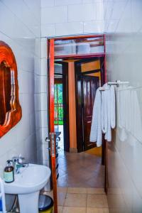 baño con lavabo, aseo y puerta en Savani Apartments, Kabale., en Kabale