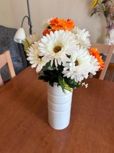 un jarrón blanco lleno de flores blancas y naranjas sobre una mesa en Apartamento Isabel, en Cuenca