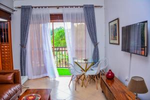 ein Wohnzimmer mit einem Tisch, Stühlen und einem Fenster in der Unterkunft Savani Apartments, Kabale. in Kabale