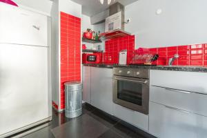 cocina con azulejos rojos en las paredes en appartement de la barque bleue, en Le Grau-du-Roi