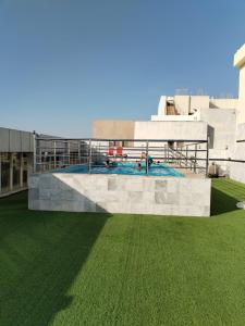 a swimming pool on top of a building with green grass at Paradise Inn Jeddah Hotel in Jeddah